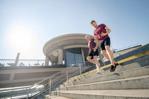 Genç erkek ve gri saçlı erkek spor yapıyor, merdivenlerden aşağı koşuyor. — Stok fotoğraf