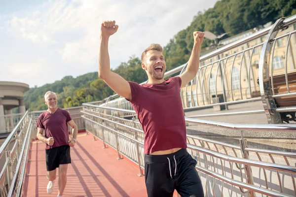 Junger bärtiger Mann hebt beide Hände und gewinnt Laufrennen — Stockfoto