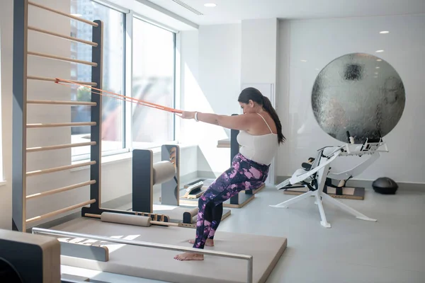 Brunette jong plus size vrouw stretching de riemen met inspanningen — Stockfoto