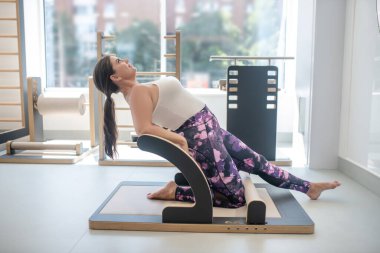 Bir kadın spor salonunda sırt kaslarını esnetiyor.