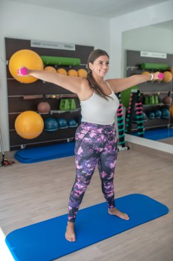 Spor salonunda yoga yapan iri yarı bir kadın.