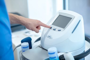 Fizyoterapi ultrason makinesinin düğmelerine basan erkeklerin yakın çekim görüntüleri.