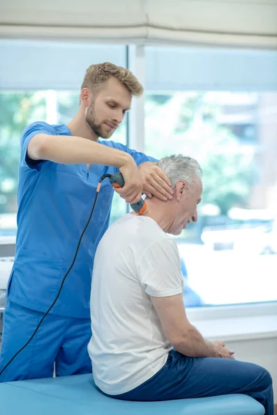 Mladý vousatý lékař provádějící ultrazvukové ošetření krku u mužského pacienta — Stock fotografie