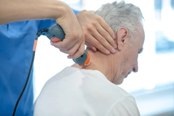Вид ззаду сіро-волосий чоловічий пацієнт, який отримує ультразвукове лікування шиї — стокове фото