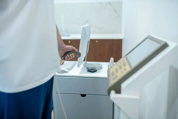 Hombre en camiseta blanca cerca del aparato médico sin rostro — Foto de Stock