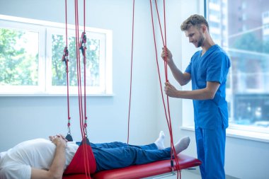 Gülümseyen genç doktor hasta rehabilitasyonuna hazırlanıyor.