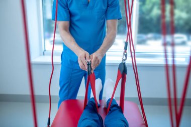 Erkek eller fizyoterapi için tıbbi kayışı tutuyor.