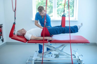 Hastanın yanındaki kanepede genç bir doktor var.