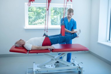 Ayakları havada yatan yaşlı hasta ve doktor.