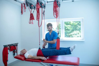 Tıp merkezinde esneme seansı yapan yaşlı bir adam.