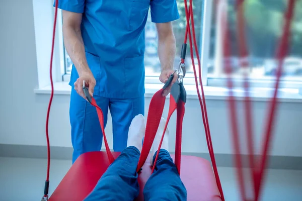 Kezét orvos tartja öv körül a betegek lábát — Stock Fotó