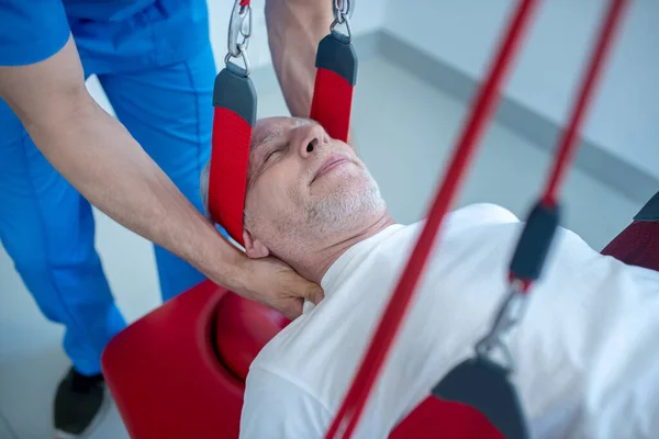 Руки лікаря-чоловіка, що масажує шию літнього пацієнта — стокове фото
