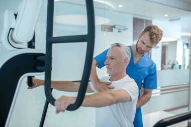 Simülatör ve eğitmenin korkuluklarında el ele tutuşan adam.