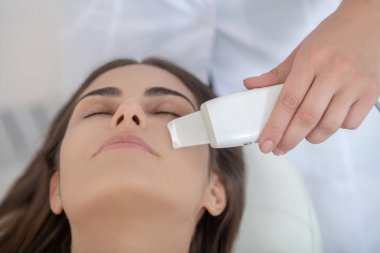 Koyu renk saçlı kadın kuaförde lazer tedavisi görüyor.