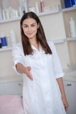 Genç kozmetolog müşteriyle tanışıyor ve elini uzatıyor.