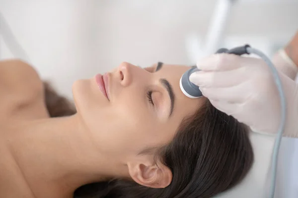 Young woman lying down with eyes closed during professional beauty procedures — Stock Photo, Image