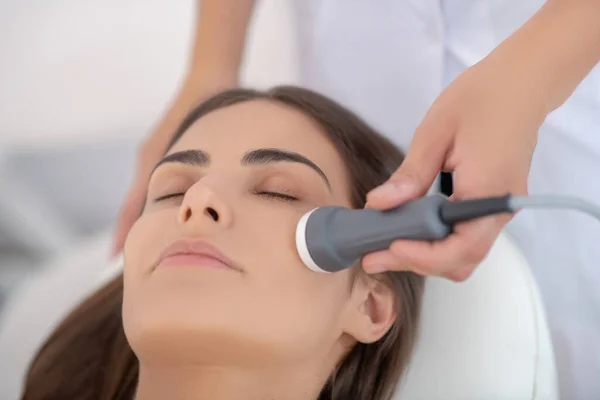 Cosmetologo che fa lisciatura di faccia laser al cliente femminile — Foto Stock