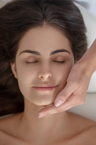 Young pretty woman having face massage and looking relaxed — Stock Photo, Image