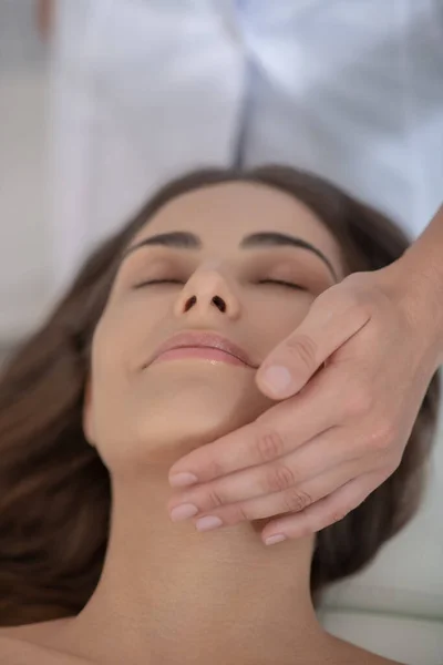 Young pretty woman having face massage and feeling relaxed