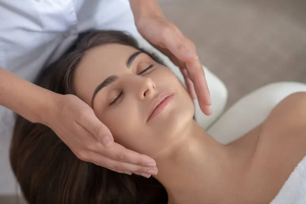Profesionální masážní terapeut provádějící masáž obličeje zákazníkovi — Stock fotografie