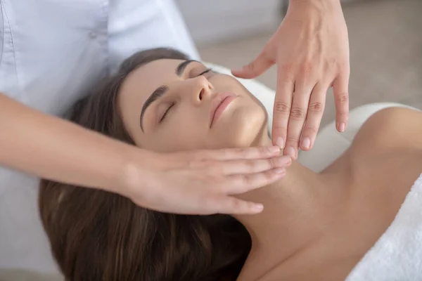 Professionele massage therapeut masseren gezicht van een vrouw — Stockfoto