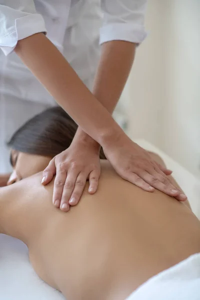 Mujer joven acostada y teniendo masaje de espalda — Foto de Stock