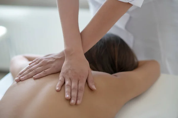 Mujer joven acostada y teniendo masaje de espalda superior — Foto de Stock