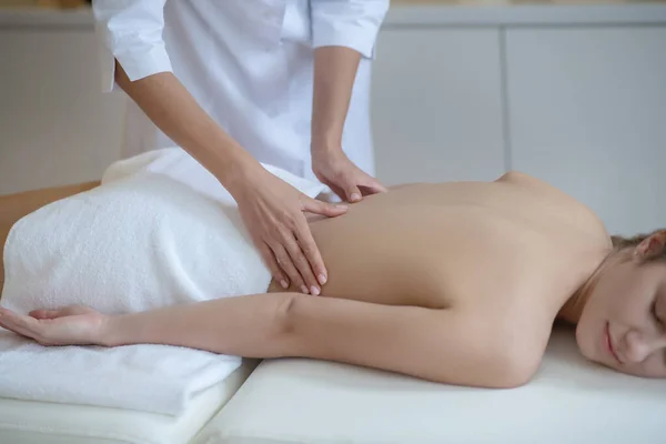 Massagetherapeutin massiert junge Frauen sanft im unteren Rücken — Stockfoto