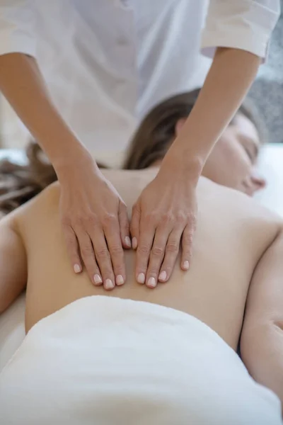 Massagetherapeutin im Laborkittel reibt Frauen sanft zurück — Stockfoto