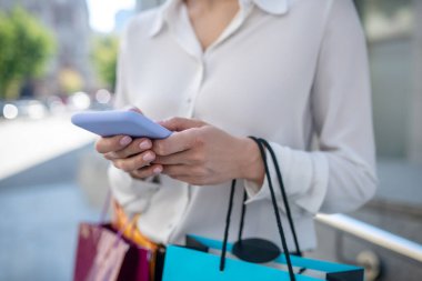 Akıllı telefon tutan bir kadının yakın plan fotoğrafı.