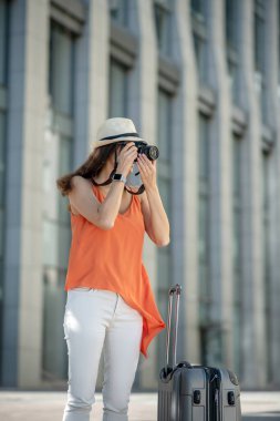 Siyah saçlı, şapkalı genç bir kadın film yapıyor.