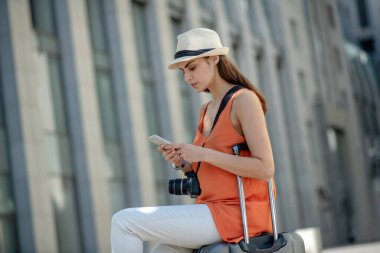 Siyah saçlı, şapkalı, mesaj yazan genç bir kadın.