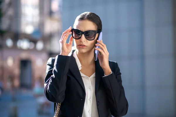 Mulher de cabelos escuros elegante olhando preocupado ao falar ao telefone — Fotografia de Stock