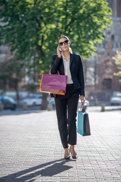 Mulher de cabelos escuros elegante com sacos de compras andando na rua — Fotografia de Stock