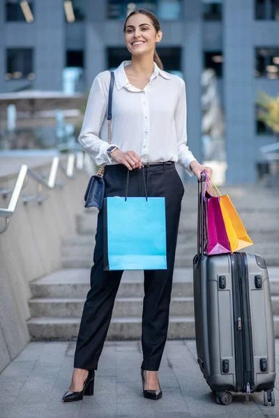 Frau im weißen Hemd steht neben dem Koffer und lächelt — Stockfoto