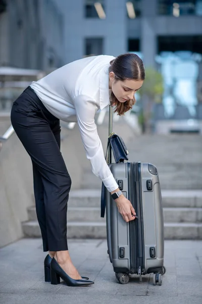 Brünette Frau im weißen Hemd mit Reißverschluss am Koffer — Stockfoto