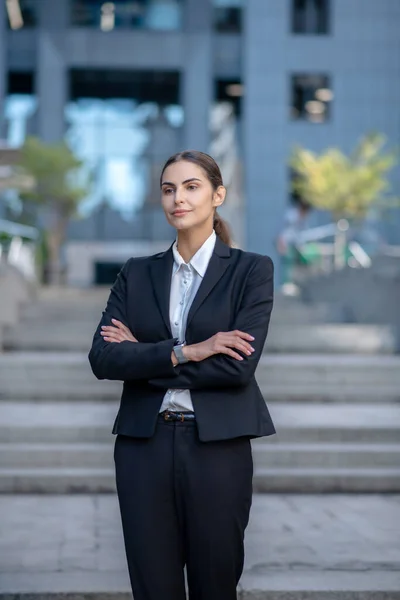 Elegante vrouw in een pak met gevouwen armen — Stockfoto