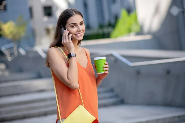 Mulher bonita em camisa laranja falando ao telefone — Fotografia de Stock