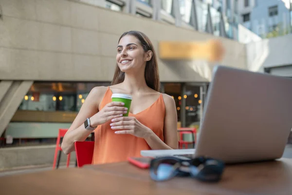 Dark-haired pretty woman holding a cup of coffee and looking aside