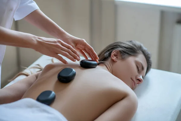 Massage therapeut zetten stenen op een klanten terug — Stockfoto