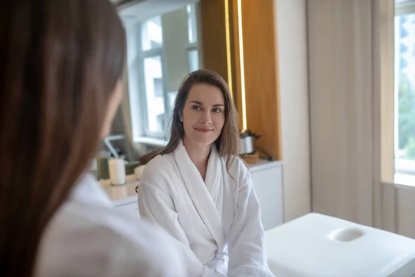 Frau im weißen Gewand diskutiert mit Kosmetikerin über Wellness-Verfahren — Stockfoto