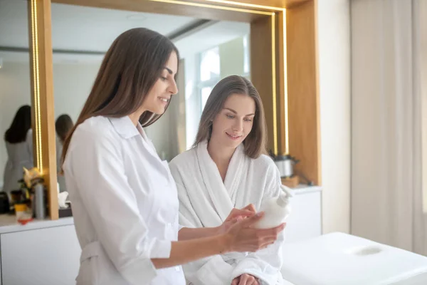 Vrouwelijke cosmetoloog presenteren schoonheid product aan haar klant — Stockfoto