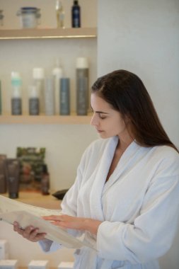 Beyaz cüppeli kadın güzellik prosedürünü seçiyor ve ilgili görünüyor.