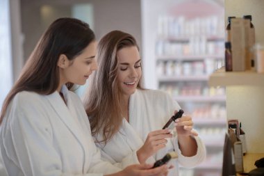 İki güzel kadın kuaförde kozmetik hakkında konuşuyor ve heyecanlı görünüyorlar.