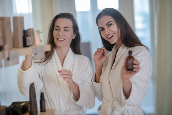 Dos mujeres bonitas mostrando cosméticos y viéndose emocionadas — Foto de Stock
