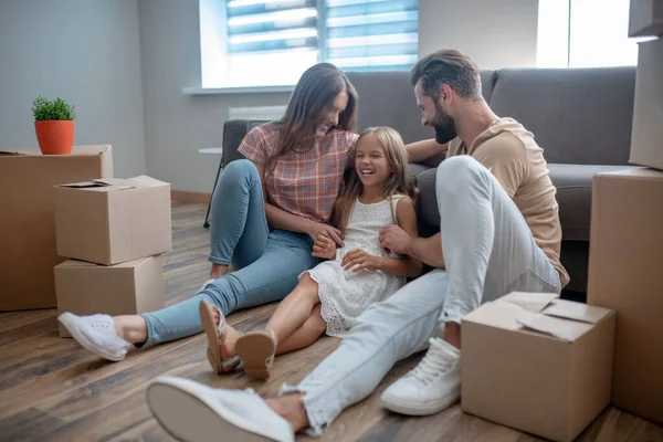 Anne ve baba kızlarını gıdıklıyor ve gülümsüyor.