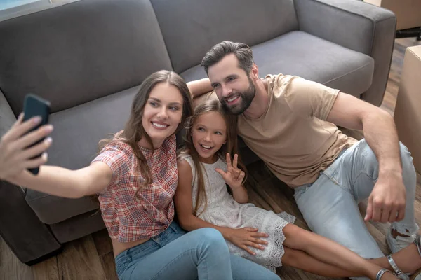 Glückliche Familie sitzt auf dem Boden und macht Selfie — Stockfoto