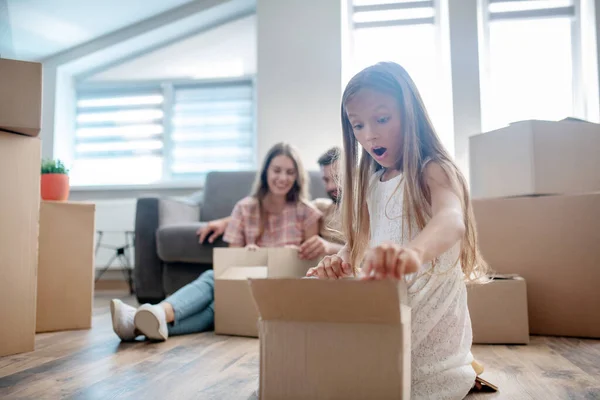 Cute girl unpacking a cardboard and looking surprised — Stock Photo, Image