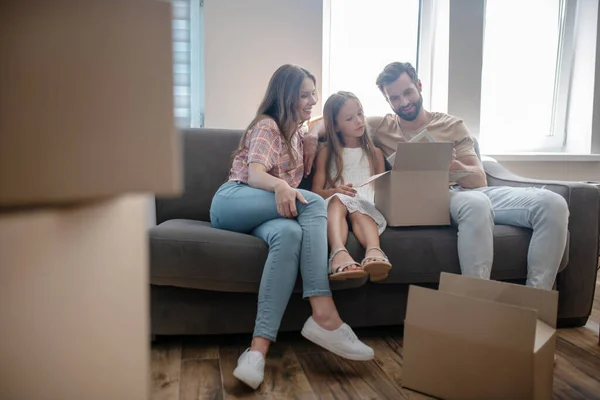 Young family sitting on the sofa and looking at the photograph — Stock Photo, Image