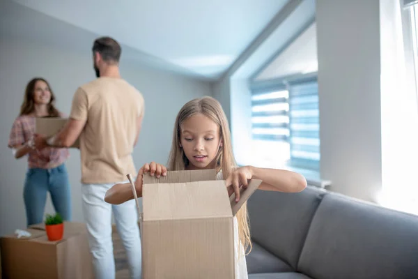 Family unpacking their stuff in a new house and looking busy — Stock Photo, Image